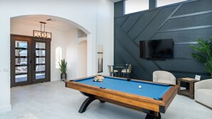 A pool table in a modern living room with a TV mounted on the wall and a potted plant. - 4400 SqFt Luxury Estate W/Pool&Spa, Billiards, Entertainment and Comfort (Lake Havasu City)