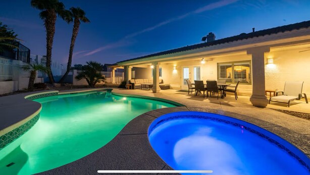 A pool area with a curved design, a patio with outdoor furniture, and a building with a tiled roof. - 4400 SqFt Luxury Estate W/Pool&Spa, Billiards, Entertainment and Comfort (Lake Havasu City)
