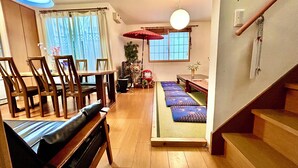 A traditional Japanese-style room with tatami mats, a low table, wooden chairs, a sofa, and a sliding door. - Shinjuku 120 sq.m. house / 3 min walk from JR Shin-Okubo station / 2 bathrooms, 2 toilets, parking / 10 min walk from Kabukicho (新宿区百人町)