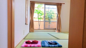 A tatami mat room with a sliding door to a balcony, a wooden floor, and a small table with a cushion. - Shinjuku 120 sq.m. house / 3 min walk from JR Shin-Okubo station / 2 bathrooms, 2 toilets, parking / 10 min walk from Kabukicho (新宿区百人町)