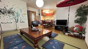 A traditional Japanese-style living room with tatami mats, a low wooden table, a TV, and a red umbrella. - Shinjuku 120 sq.m. house / 3 min walk from JR Shin-Okubo station / 2 bathrooms, 2 toilets, parking / 10 min walk from Kabukicho (新宿区百人町)