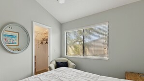 Un dormitorio con cama, una silla, un armario y una ventana con persianas.