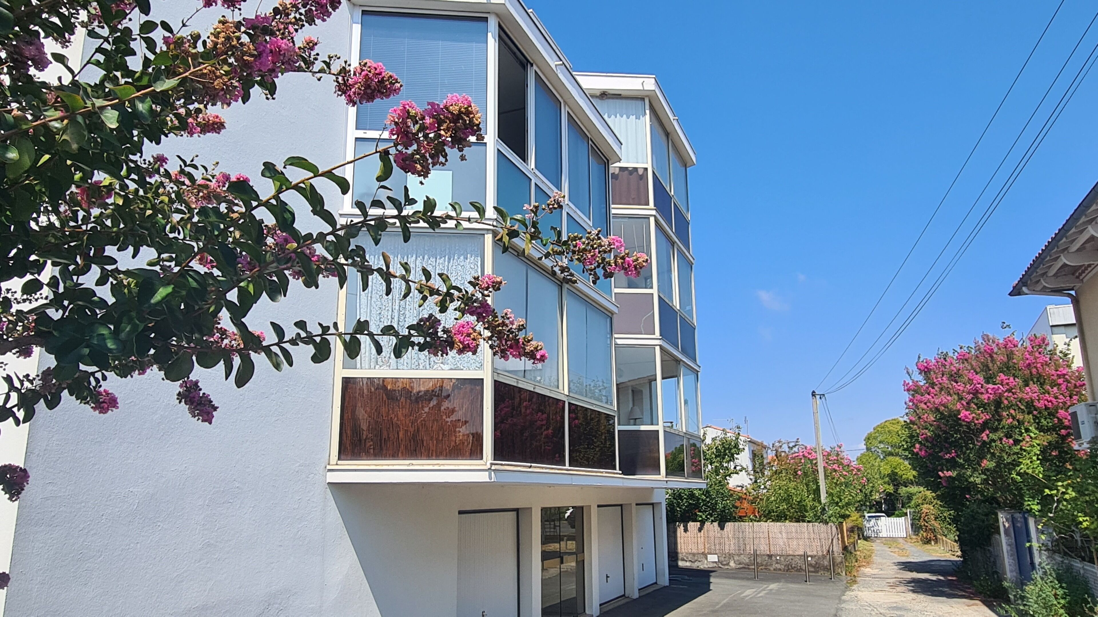 A multi-story building with balconies, a gated entrance, and a clear sky.
