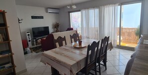 Zona pranzo con tavolo, sedie, televisore e libreria.