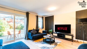 Moderni olohuone, jossa on sohva, sohvapöytä ja televisio, jonka näytöllä näkyy teksti ”NETFLIX”.