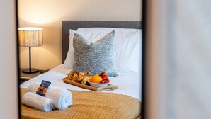 Siisti hotellihuone, jossa on valmiiksi pedattu sänky, hedelmävati ja pyyhe.