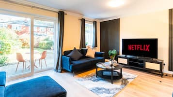 A modern living room with a sofa, coffee table, and a TV displaying 'NETFLIX'.
