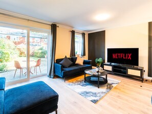 A modern living room with a sofa, coffee table, and a TV displaying 'NETFLIX'.