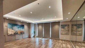 A spacious room with a wooden floor, recessed ceiling lights, and large windows.