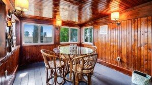 Ein Zimmer mit Holzwänden, einem runden Glastisch und Korbstühlen, großen Fenstern und einem Schild mit der Aufschrift 'Whatever floats will float'.