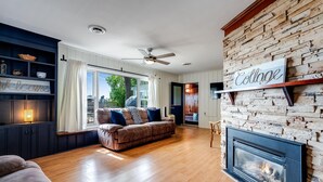 Ein gemütliches Wohnzimmer mit Kamin, einer Couch und einem großen Fenster.