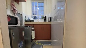 Cuina petita amb microones, nevera i finestra que ofereix una vista.