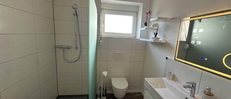 Une salle de bain avec douche, toilettes et lavabo.