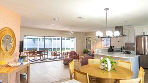 Una cocina amplia con una isla central, un comedor con una mesa redonda y un espacio de sala de estar con un sofá y sillones.