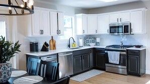 A modern kitchen with white cabinets, a stainless steel stove, and a microwave. - Charming 3-Bedroom, 2-Bath Home with Office – Just 7 Min to Downtown McKinney! (McKinney)