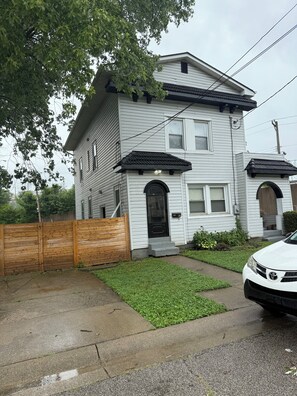 A two-story house with a front porch, a wooden fence, and a car parked in the driveway. - stylish and spacious three-story getaway three bedrooms, two full baths. (cincinnati)