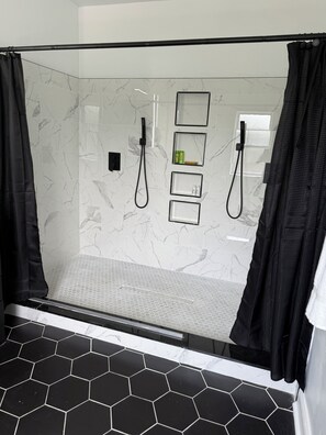 A modern shower area with a glass enclosure, black shower curtains, and a tiled floor with hexagonal patterns. - stylish and spacious three-story getaway three bedrooms, two full baths. (cincinnati)