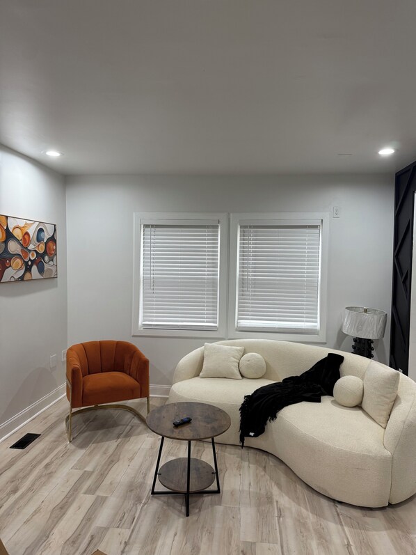 A modern living room with a beige sofa, a round coffee table, and an orange armchair. - stylish and spacious three-story getaway three bedrooms, two full baths. (cincinnati)