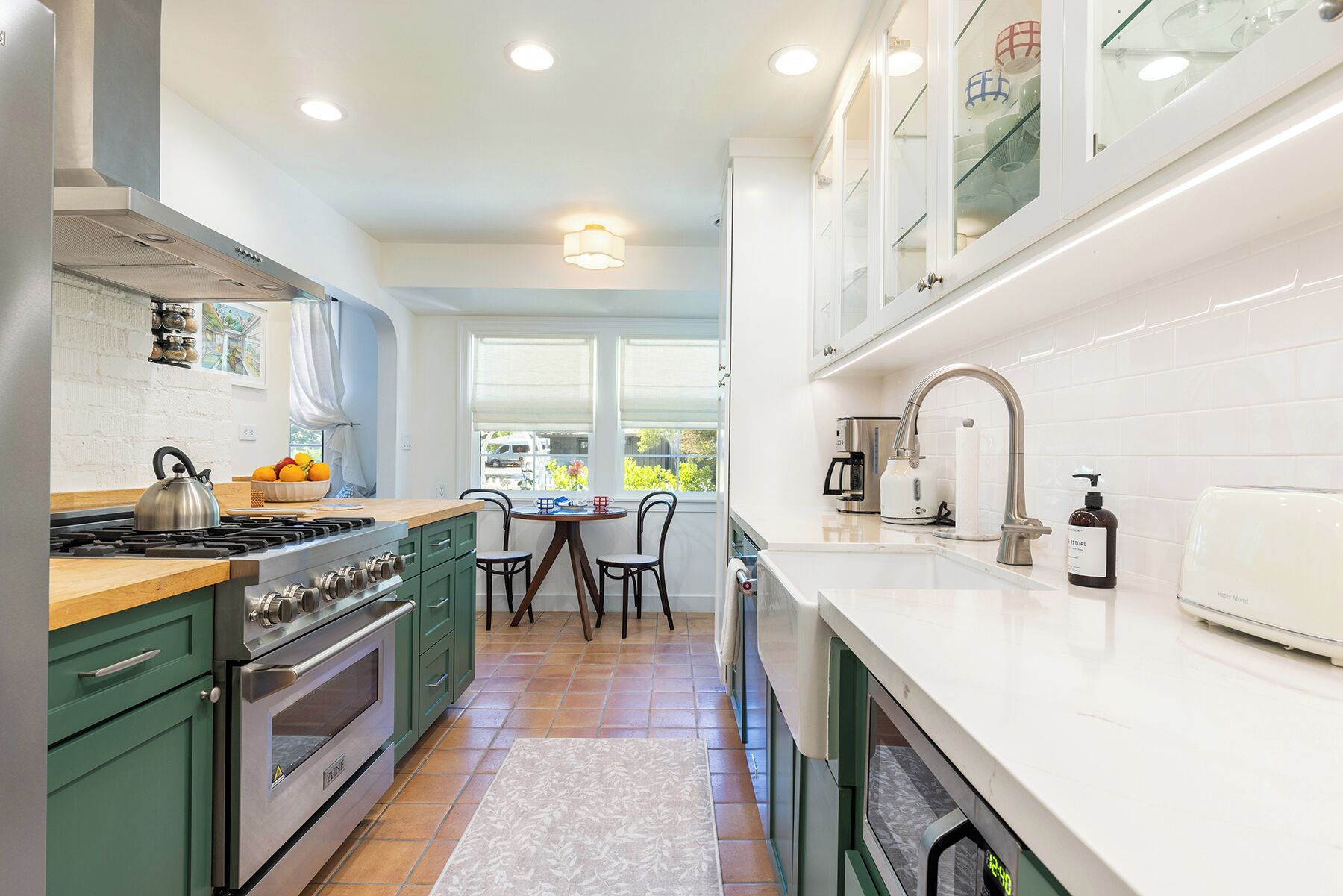 A modern kitchen with a gas stove, oven, and a dining area with a table and chairs.