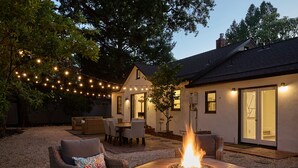 Een terras met een vuurkuil, lichtjes en tuinmeubilair.