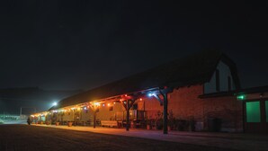 A building with a covered outdoor area, a brick wall, and a green-lit door.