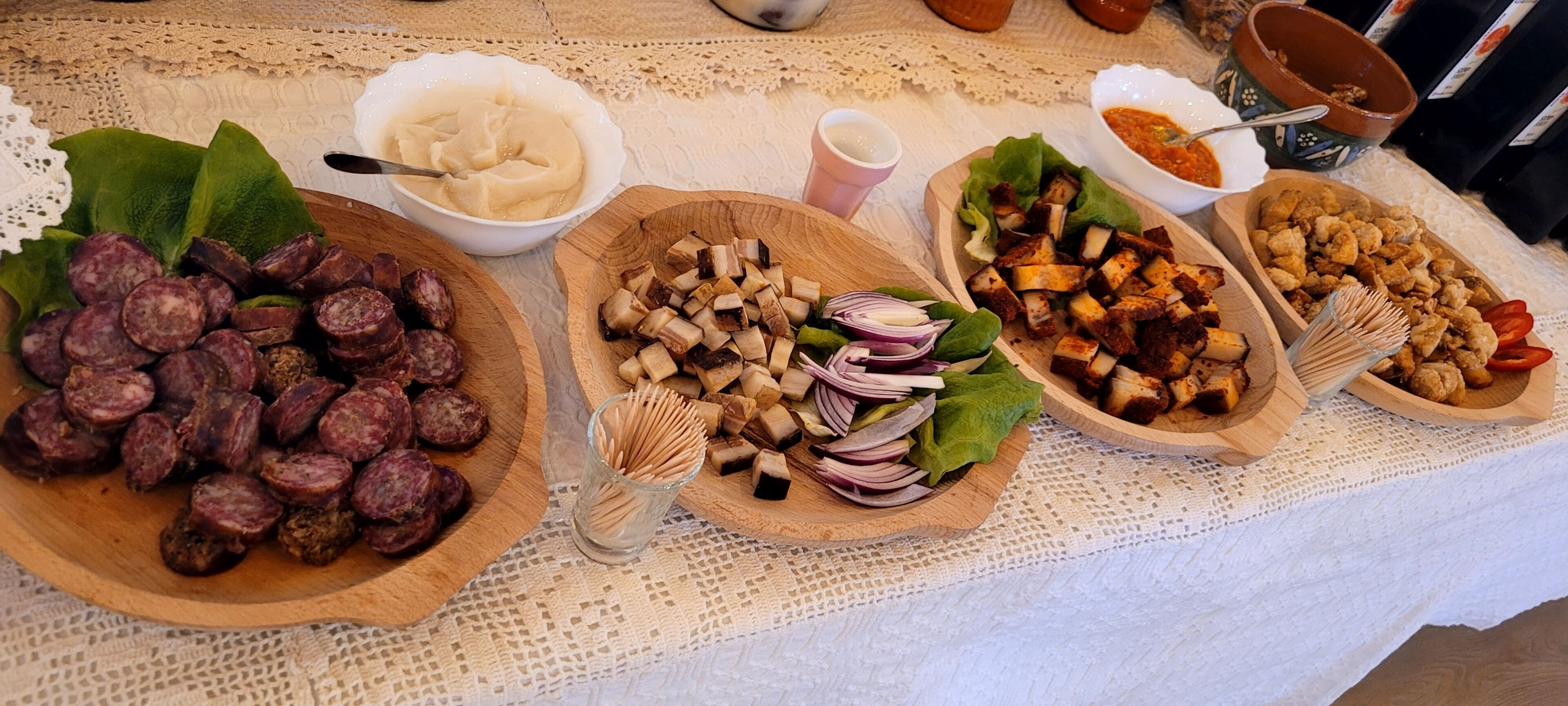 A table with various food items, including sliced sausages, tofu, and vegetables.