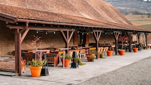 A building with a tiled roof, outdoor seating, and potted plants. - Sólyom Major - Gut Falkenhof (Sacel)