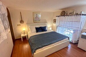 A bedroom with a bed, bedside table, lamp, and a window with a curtain. - Perfectly located in the heart of Rome, transportation right outside your door (Roma)