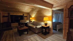Ein gemütliches Blockhaus-Interieur mit einer Couch, zwei Lampen, einem kleinen Tisch und einem Korb.