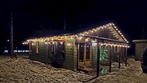 Eine Holzhütte mit überdachter Veranda, einer kleinen Terrasse und einem Weihnachtsbaum.
