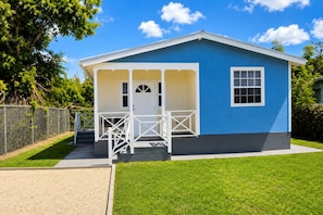 A small, single-story building with a blue exterior and a white porch.