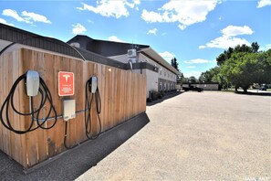 A vehicle charging station with a wooden fence and a sign indicating it is for electric vehicles only. - Willowbend Hotel (Maple Creek)