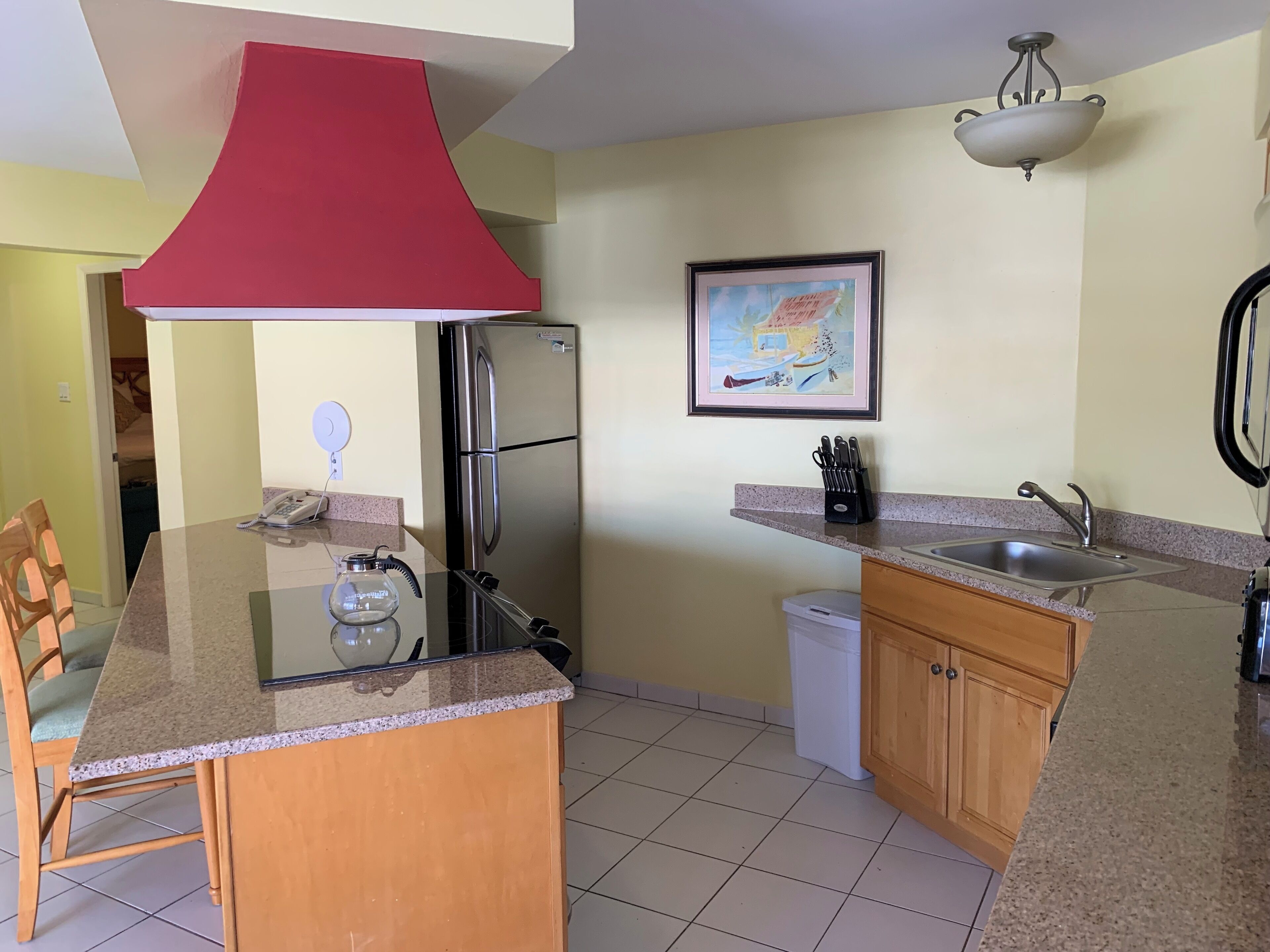 A compact kitchen with a central island, a refrigerator, a sink, and a dining area with chairs.