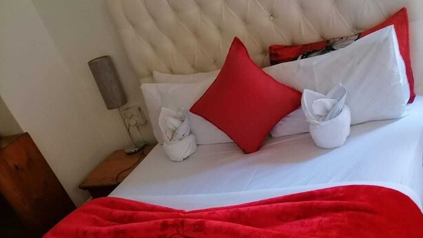 A neatly made bed with white linens and a red throw blanket. - Neo & Ruks Guest House Parow (Cape Town)
