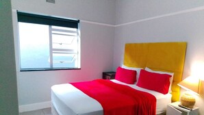 A hotel room with a bed, a window, and a nightstand. - Neo & Ruks Guest House Parow (Cape Town)