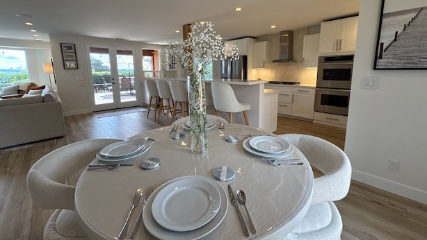A modern dining area with a round table set for four, surrounded by white chairs. - SLO 2BR/1BA + Bonus Room, Sleeps 6 I Close to Downtown and Cal Poly (San Luis Obispo)