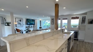 A modern kitchen with a large marble island, wooden column, and built-in appliances. - SLO 2BR/1BA + Bonus Room, Sleeps 6 I Close to Downtown and Cal Poly (San Luis Obispo)
