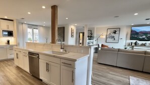 A modern kitchen with white cabinetry, a central island, and a built-in dishwasher. - SLO 2BR/1BA + Bonus Room, Sleeps 6 I Close to Downtown and Cal Poly (San Luis Obispo)