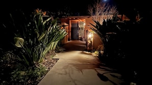 A nighttime view of a house entrance with a pathway leading to a door, surrounded by various plants and illuminated by exterior lighting. - SLO 2BR/1BA + Bonus Room, Sleeps 6 I Close to Downtown and Cal Poly (San Luis Obispo)