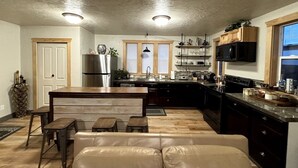 A kitchen with a central island, wooden cabinets, a stainless steel refrigerator, and a microwave. - Charming 2-bedroom house in beautiful Somers with AC (Somers)