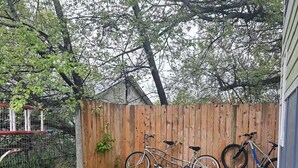 A backyard with a wooden fence, two bicycles, a round table, and outdoor seating. - Charming 2-bedroom house in beautiful Somers with AC (Somers)
