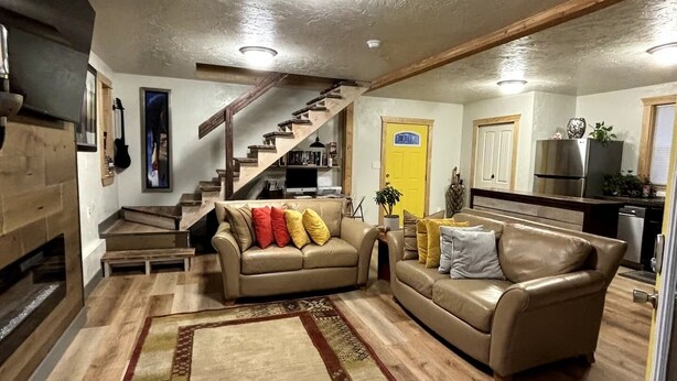 A spacious living area with a large rug, a staircase, and a kitchen in the background. - Charming 2-bedroom house in beautiful Somers with AC (Somers)