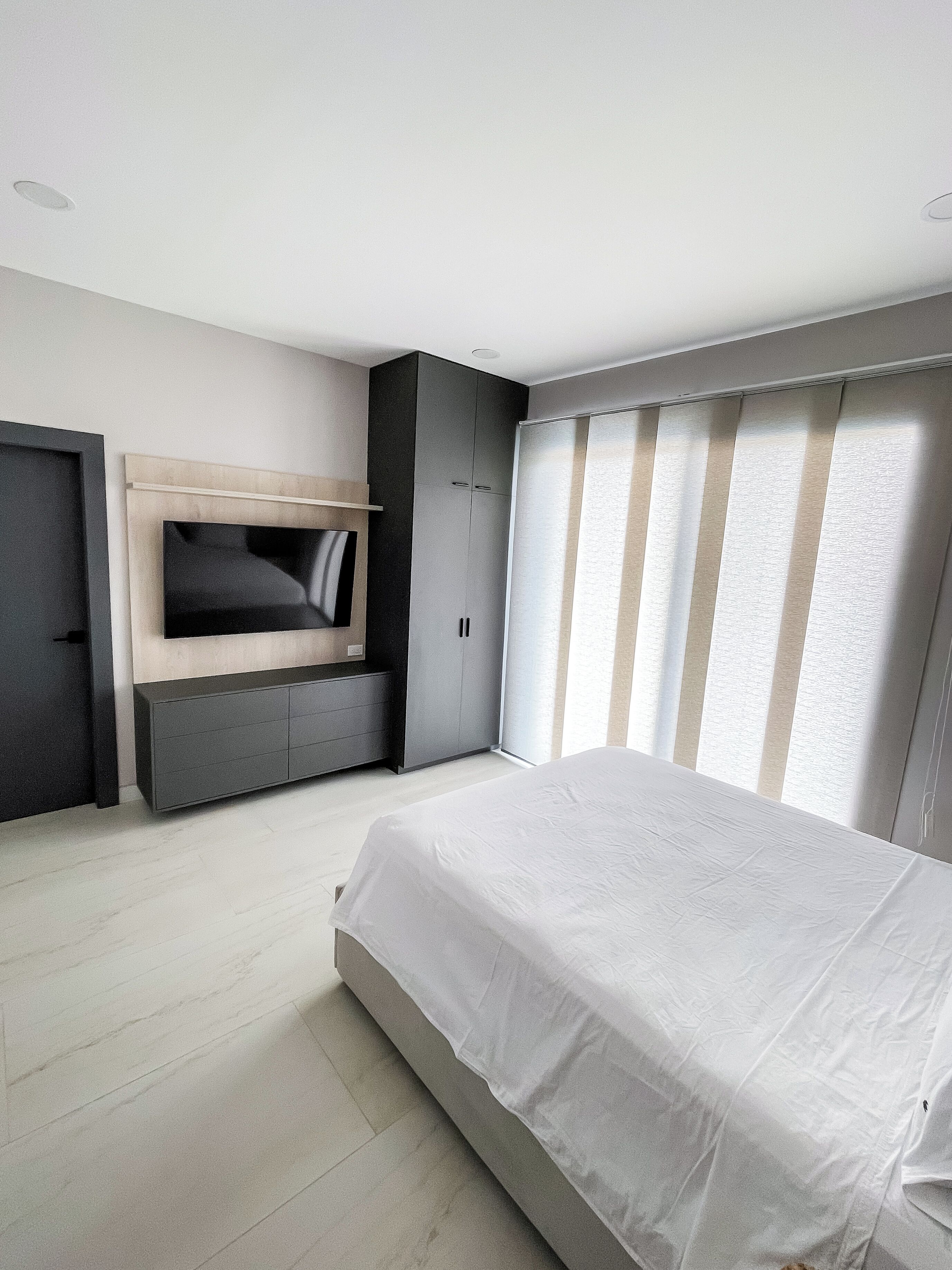 Une chambre à coucher moderne, équipée d’un lit, d’une armoire intégrée et d’un téléviseur.
