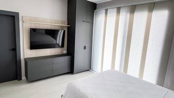 Une chambre à coucher moderne, équipée d’un lit, d’une armoire intégrée et d’un téléviseur.