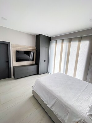 Een moderne slaapkamer met een bed, inbouw kast en een televisie.