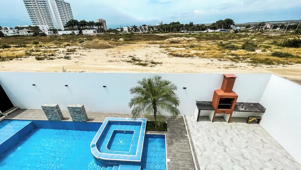 A rooftop pool with a view of the beach and buildings. - La Vie Es Belle Beach House (Santa Eleana)