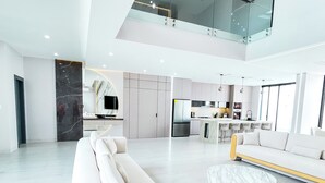 A spacious living area with a modern sofa, a marble coffee table, and a kitchen in the background. - La Vie Es Belle Beach House (Santa Eleana)