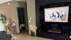 Un salon moderne avec un canapé d’angle gris, une table basse en bois et un meuble noir pour la télévision.