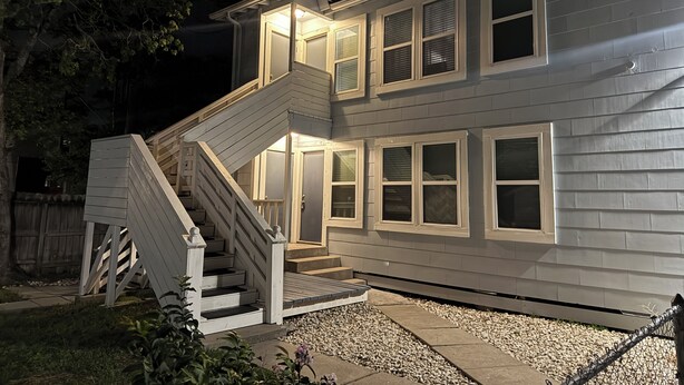 A two-story house with a staircase leading to the front door, a covered porch, and a fenced backyard. - Charming duplex - convenient, comfortable, Close to It All. Beach, Work & Play! (Corpus Christi)