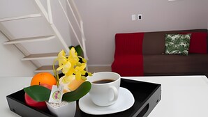 Uma bandeja com uma xícara de café branca, um pequeno vaso de planta e uma laranja sobre uma mesa branca.
